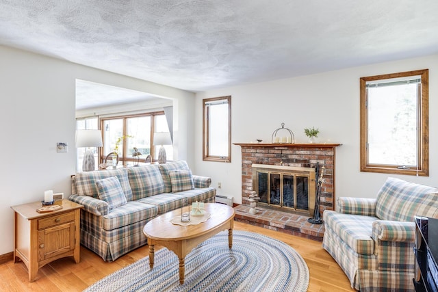living room with light wood-style flooring, a fireplace, and a baseboard radiator