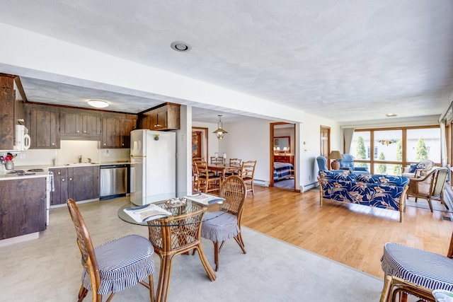 dining space with baseboard heating, a textured ceiling, baseboards, and light wood-style flooring