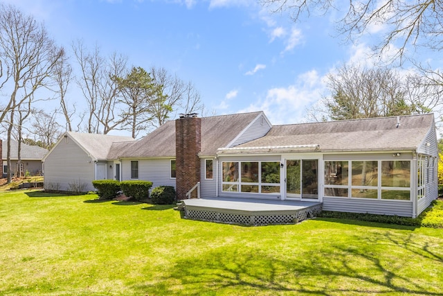 back of property with a sunroom, a lawn, a chimney, and a wooden deck