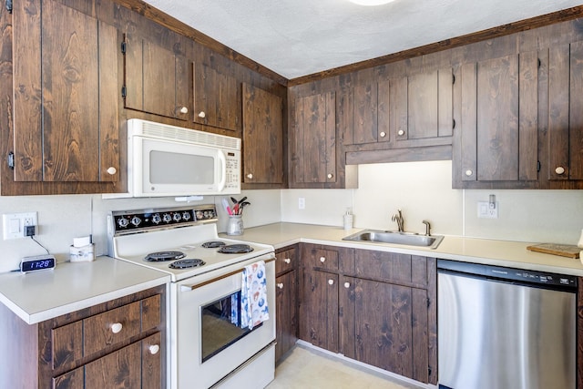 kitchen featuring white appliances, a sink, light countertops, and dark brown cabinets