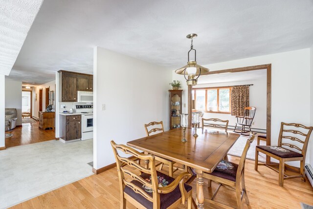 dining space with light wood finished floors, baseboard heating, and baseboards