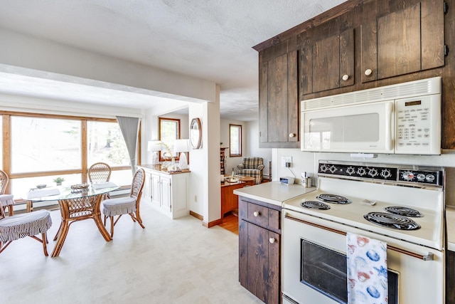 kitchen with white appliances, light countertops, dark brown cabinets, baseboards, and a textured ceiling