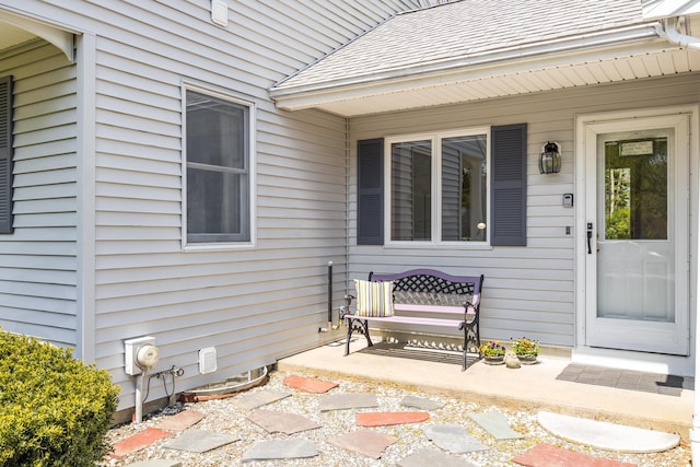 doorway to property with a shingled roof and a porch
