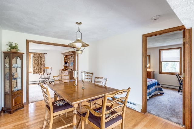 dining space with a baseboard heating unit and light wood-type flooring
