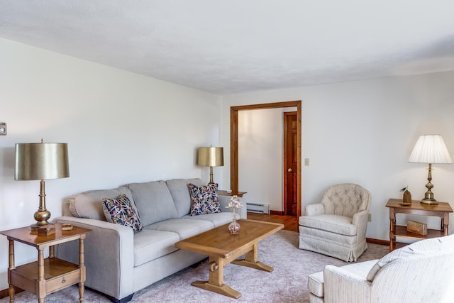 carpeted living room featuring a baseboard heating unit and baseboards