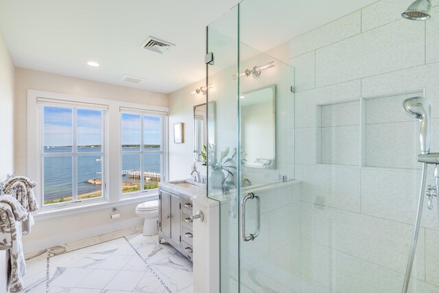 bathroom with a shower with shower door, toilet, vanity, and a water view