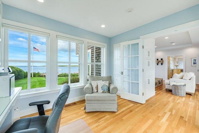 sitting room with a water view and light wood-type flooring