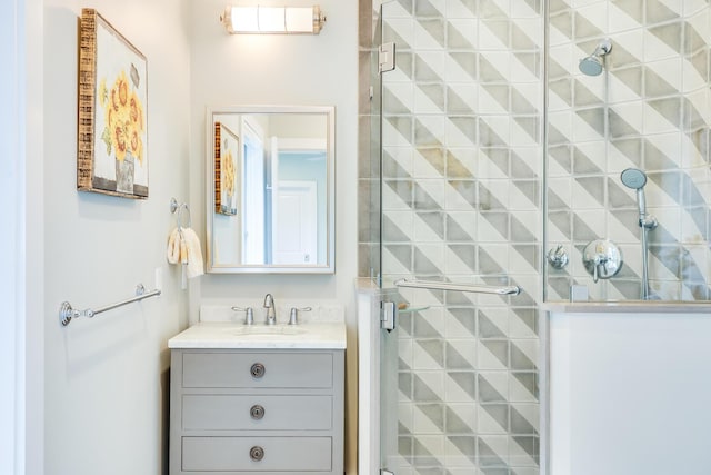 bathroom featuring a shower with shower door and vanity