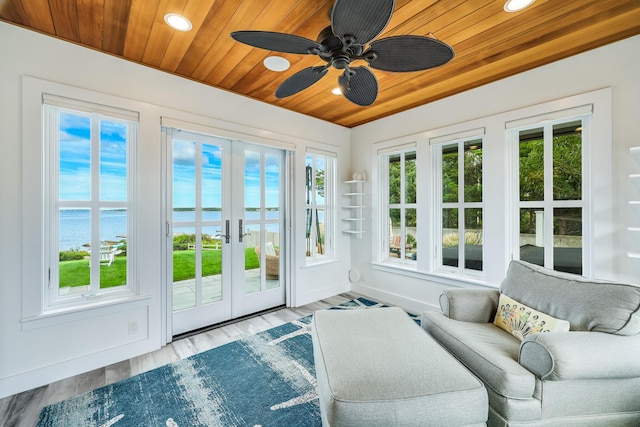 sunroom featuring ceiling fan, plenty of natural light, french doors, and a water view