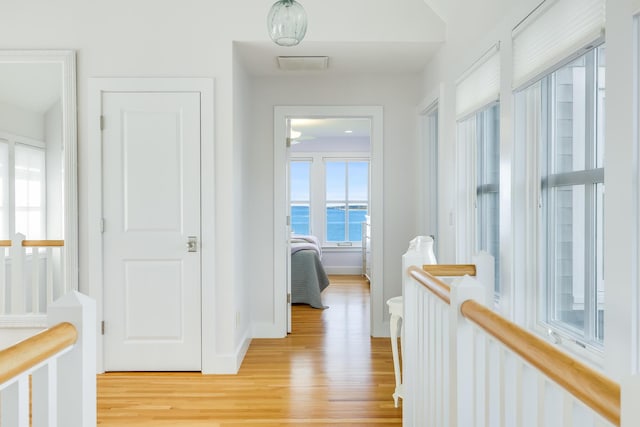 corridor with light wood-type flooring and a water view