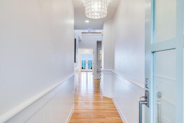 corridor with light hardwood / wood-style flooring and an inviting chandelier