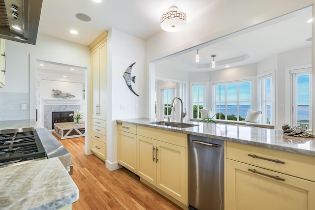 kitchen with sink, light wood-type flooring, cream cabinets, and a healthy amount of sunlight