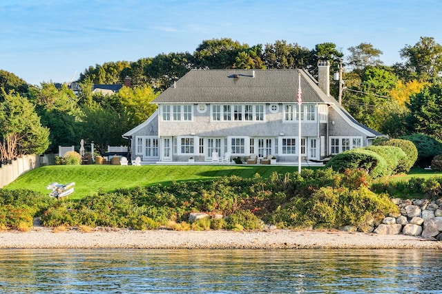 back of property featuring french doors, a lawn, and a water view