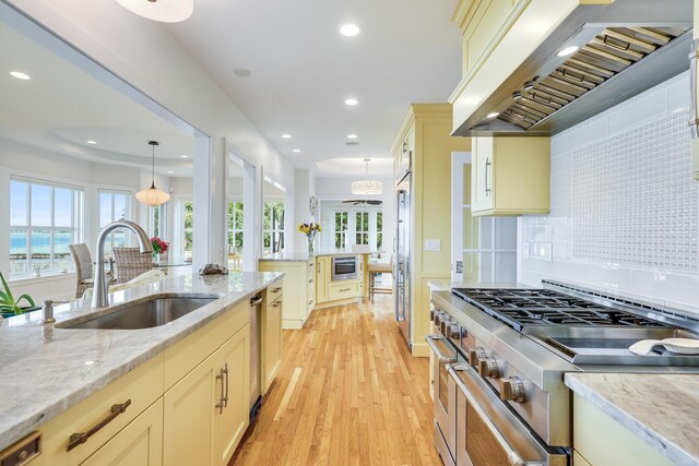 kitchen with pendant lighting, premium appliances, premium range hood, backsplash, and sink