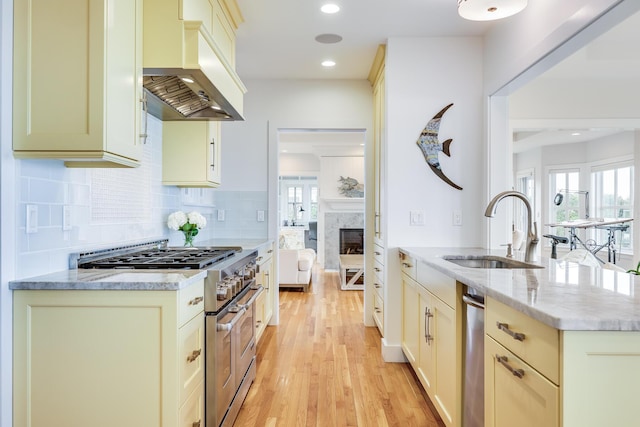 kitchen with premium range hood, high end stainless steel range oven, sink, and light stone countertops