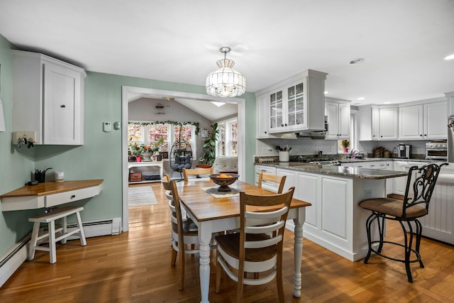 dining space featuring wood finished floors, vaulted ceiling, recessed lighting, and a chandelier