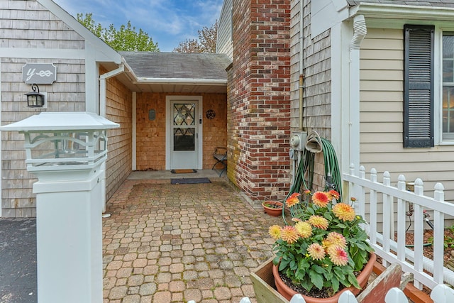 doorway to property with a shingled roof
