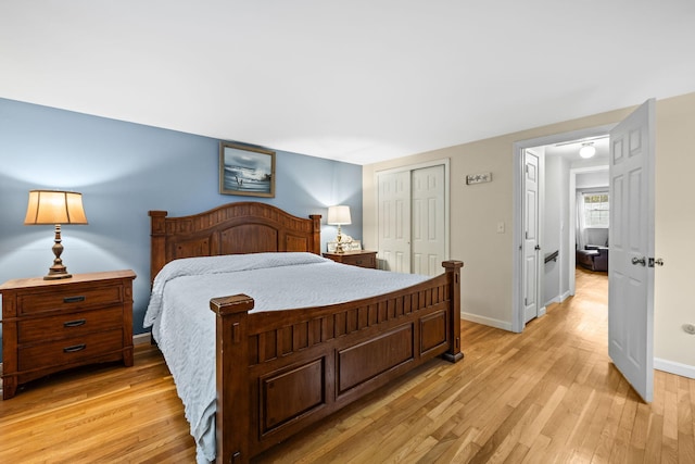 bedroom with light wood-style flooring, a closet, and baseboards