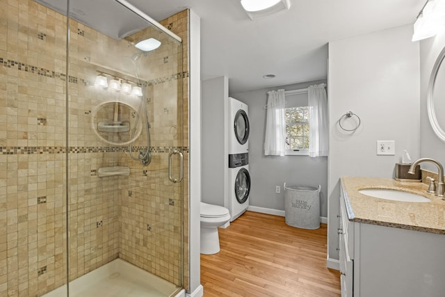 bathroom with stacked washer / dryer, a stall shower, wood finished floors, and vanity