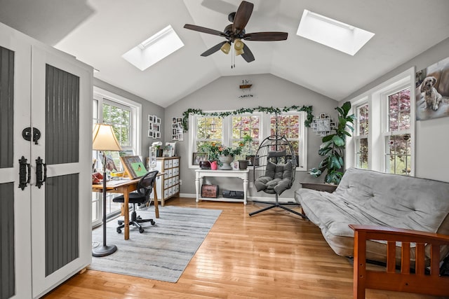 office space featuring a skylight, a ceiling fan, lofted ceiling, and light wood-style floors