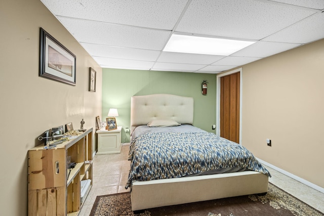 bedroom with a drop ceiling and light tile patterned flooring