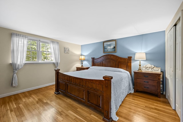bedroom with light wood-style floors, baseboards, and a closet