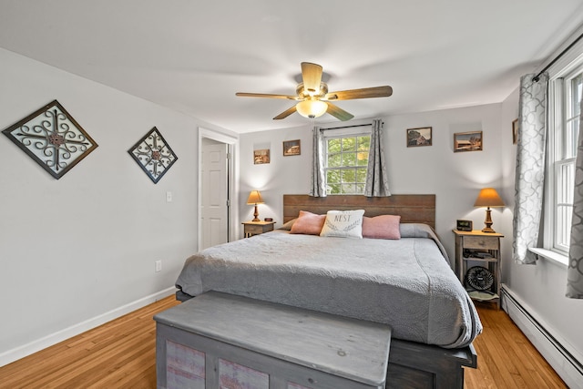 bedroom with baseboard heating, light wood finished floors, a ceiling fan, and baseboards