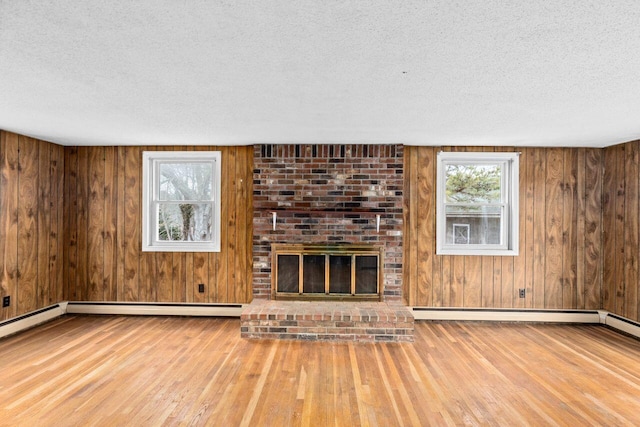 unfurnished living room featuring a textured ceiling, wood finished floors, wood walls, and a fireplace