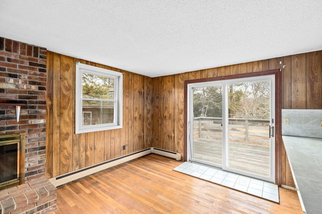 interior space featuring a baseboard radiator, a healthy amount of sunlight, light wood finished floors, and a textured ceiling