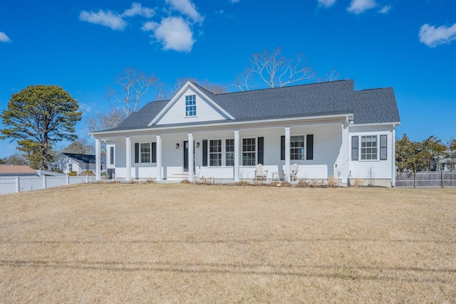 view of front facade with a front yard, fence, covered porch, and a shingled roof