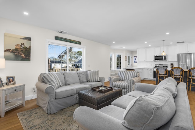 living area with recessed lighting, visible vents, and light wood-style floors