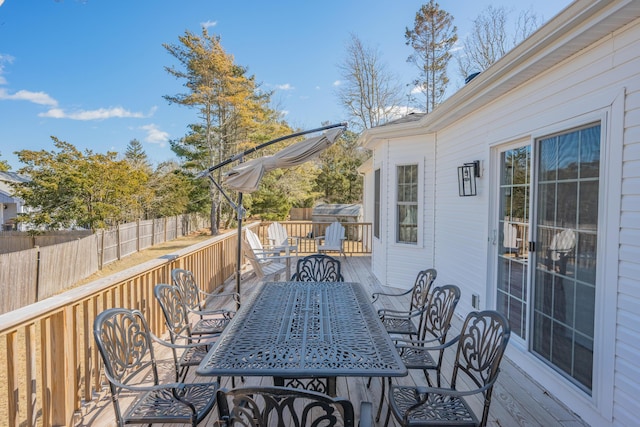 wooden terrace with outdoor dining area and fence