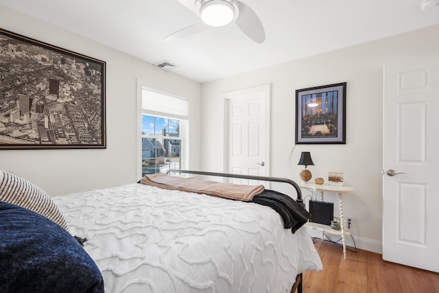 bedroom featuring ceiling fan, wood finished floors, visible vents, and baseboards