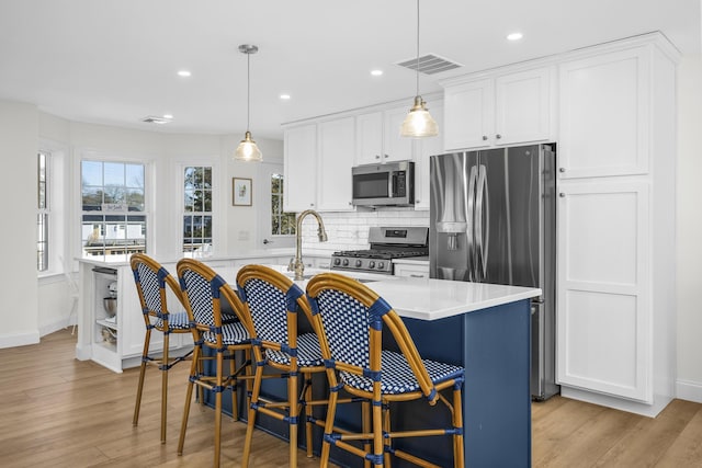 kitchen featuring tasteful backsplash, visible vents, light countertops, stainless steel appliances, and white cabinetry