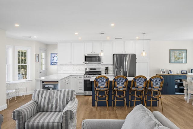 kitchen with visible vents, backsplash, white cabinetry, and stainless steel appliances