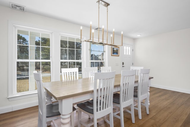 dining space with visible vents, baseboards, an inviting chandelier, and wood finished floors