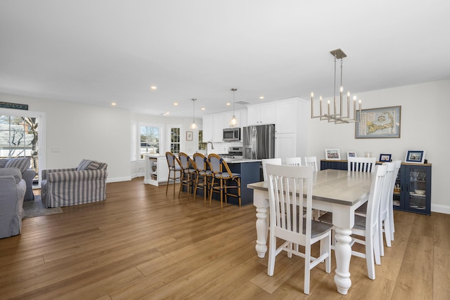 dining area featuring recessed lighting, baseboards, a notable chandelier, and light wood-style flooring