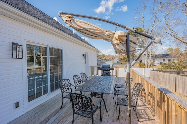 deck with outdoor dining space, grilling area, and fence