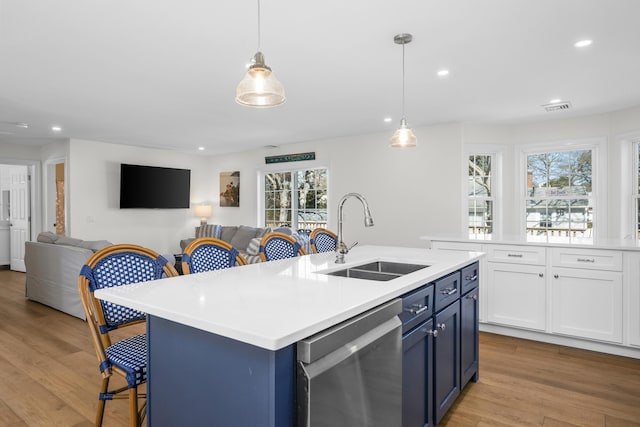 kitchen featuring stainless steel dishwasher, blue cabinetry, light wood-style floors, and a sink