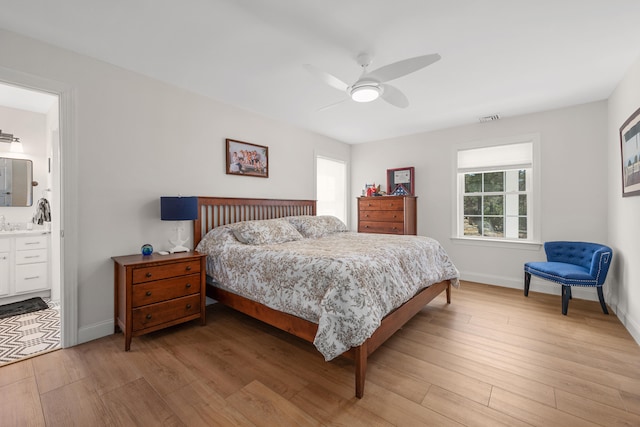 bedroom featuring visible vents, baseboards, ceiling fan, ensuite bathroom, and light wood-type flooring