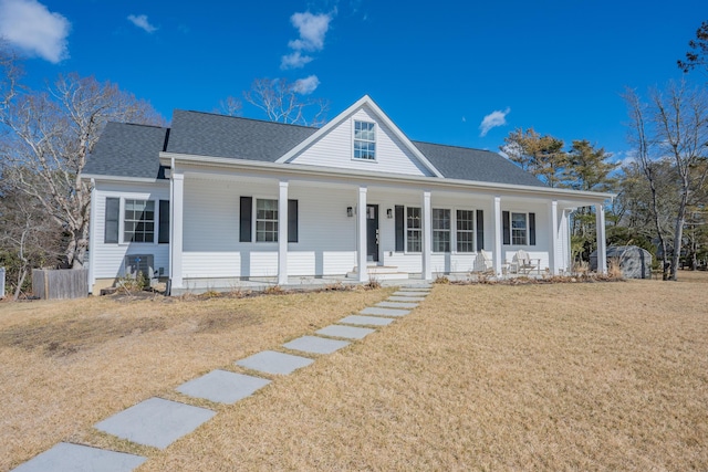 view of front of home featuring a porch, a shingled roof, a front yard, and fence