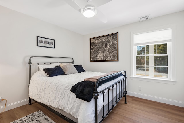 bedroom with visible vents, baseboards, wood finished floors, and a ceiling fan