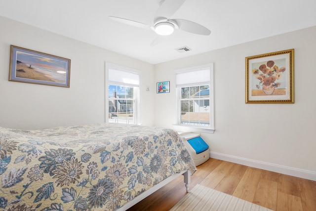 bedroom with visible vents, light wood-style flooring, a ceiling fan, and baseboards