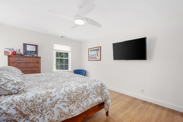 bedroom with visible vents, wood finished floors, baseboards, and ceiling fan