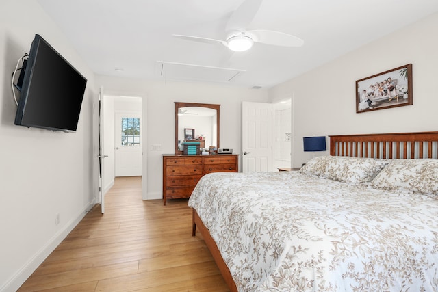 bedroom featuring light wood-style flooring, attic access, baseboards, and a ceiling fan