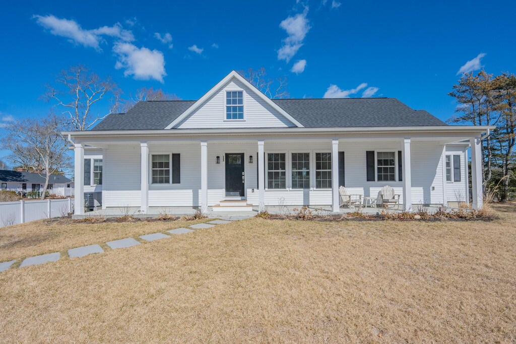 view of front of property with roof with shingles, a porch, a front lawn, and fence