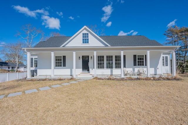 view of front of property with roof with shingles, a porch, a front lawn, and fence