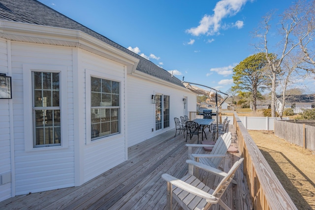 wooden terrace with outdoor dining area and a fenced backyard