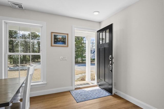 foyer entrance featuring plenty of natural light, baseboards, visible vents, and wood finished floors