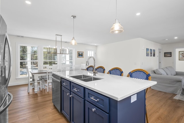 kitchen featuring a sink, stainless steel appliances, light wood-type flooring, and blue cabinets